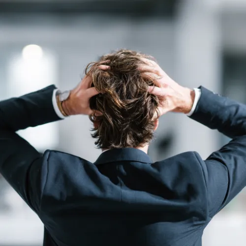 Mann hält beide Hände an den Kopf.